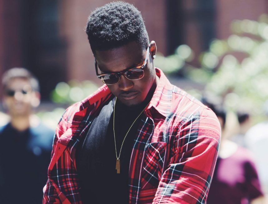 Black man with a confident look, wearing a red flannel shirt.